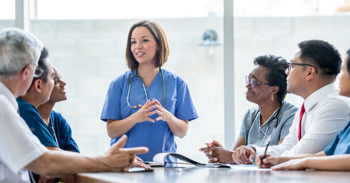 Group of medical providers talking at a table - Resuscitation Specialty Sims HealthStream